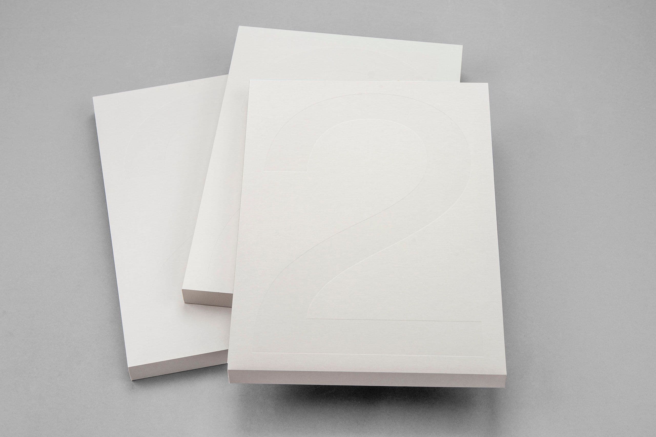 Minimalistiska böcker med vita hårdpärmar och subtil präglad numrering som visar upp exklusiva printfinishar och förfinat produktionshantverk. Bilden lyfter fram precisionspräglade detaljer, högkvalitativt papper och en ren, gedigen casebindning – idealiskt för lyxiga brandbooks, limiterade publikationer, företagsrapporter och skräddarsydda presentationsmaterial. Ett starkt exempel på bred expertis inom print och förpackning, där avancerad tryckteknik, specialfinishar och noggrant utvalda premiummaterial samverkar för att skapa högklassig varumärkeskommunikation.