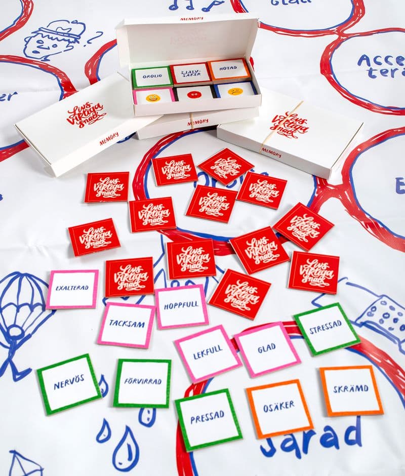 Tryckt spelplan med kort, spelpjäser och en förpackning.